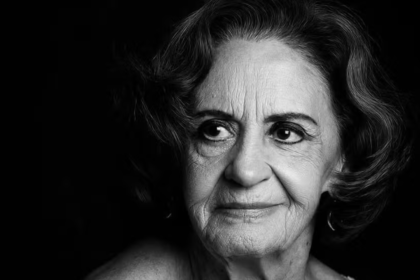 Retrato em preto e branco da atriz brasileira Laura Cardoso, com iluminação dramática vinda da esquerda, destacando as expressões faciais e marcas de idade. Ela olha para o lado com um leve sorriso. O fundo é totalmente escuro.