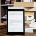 Página de livro aberta em um tablet apoiado em livros