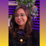 Suellen Mattos está em seu estúdio colorido, com um microfone à sua frente para a gravação de mais um podcast.