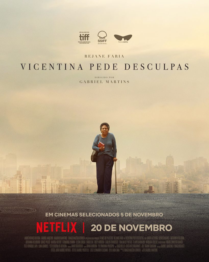 Idosa andando apoiando em uma bengala, com uma bolsa nos ombros e livros nas mãos.
